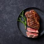 Beef,Steak,Medium,Rare,On,A,Black,Plate.,Dark,Background.