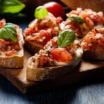 Italian,Bruschetta,With,Roasted,Tomatoes,,Mozzarella,Cheese,And,Herbs,On